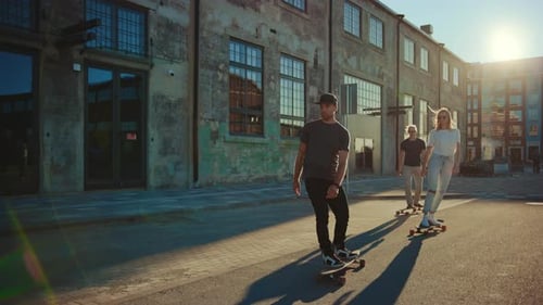 Group of Girls and Boys on Skateboards Through Fashionable Hipster District. Beautiful Young Peopl