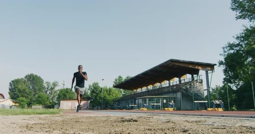 Slow motion close up of young african male athlete is performing a long jump on race track in athl