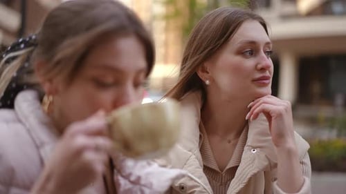 Two Young Women Talking at an Urban Cafe