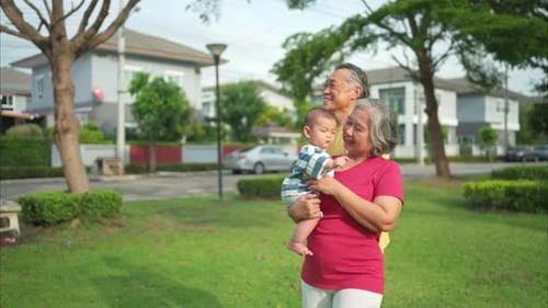 Grandparents with little child are having fun and resting in a park
