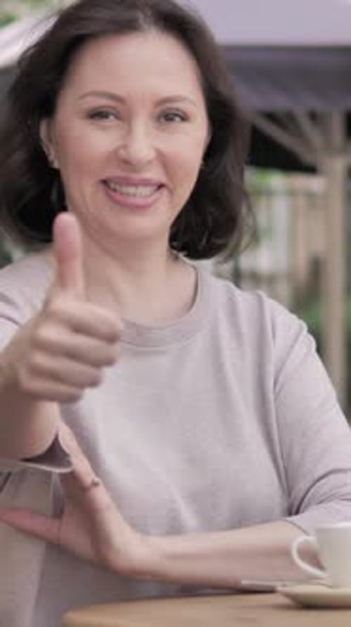 Thumbs Up by Old Woman Sitting in Outdoor Cafe, Vertical Video