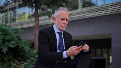 Man in Suit Using Smartphone Outdoors