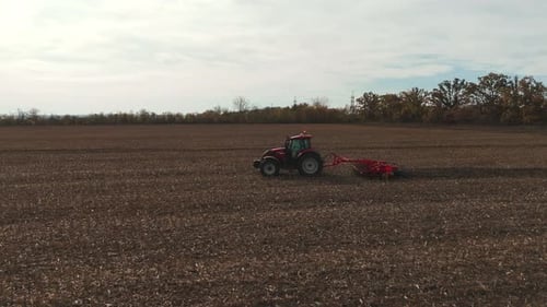 Aerial tractor plowing agricultural field preparing soil for planting farming industry concept