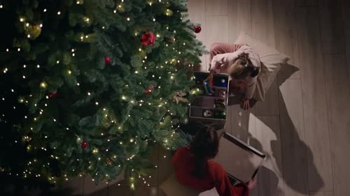 Top View of a Young Woman and a Little Girl Decorating a Christmas Tree with Ornaments and Lights