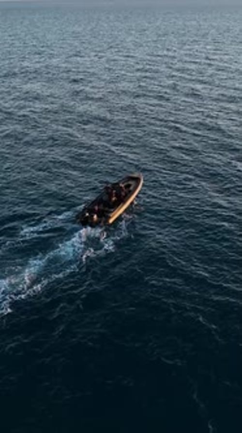 Vertikales Video Aerial Tranquility: Die Sonnenuntergangsfahrt eines Luxus-Sportboots auf dem Dunklen Meer