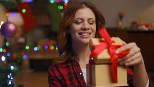 Woman Opens Christmas Gifts in Home at Christmas
