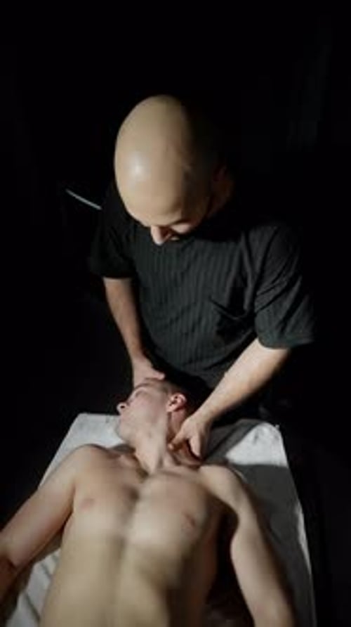 Man Receives Shoulder Massage in Dark Room
