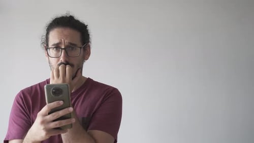 Worried Man Looking at Smartphone Indoors