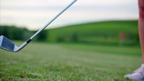 Golf club swinging back and forth on a grass field on a sunny day