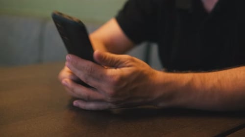 Man's Hands Holding a Smart Phone Indoors