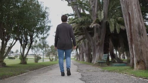 Woman Walking Away on a Path in a Park