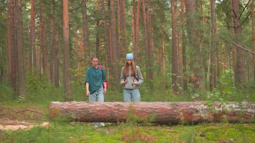 Two Sisters Hiking in Lush Green Forest with Backpacks and Sunlight Filtering