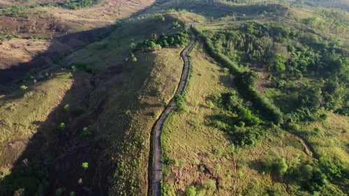 Aerial view of a winding road over a green mountain ridge