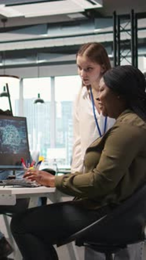 Two Women Collaborate at Computer in Modern Office