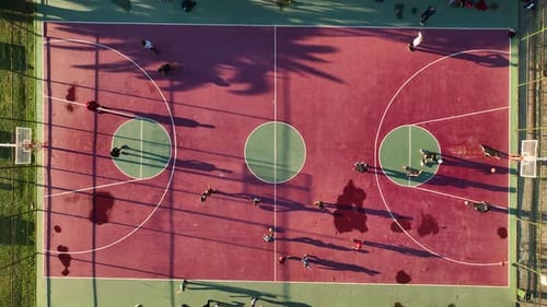Red Basketball Court Aerial View People are Actively Playing Ball Happily Enjoying the Game on a