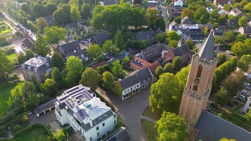 Aerial view of a charming European town with red tiled roofs, lush greenery, and a tall church tower