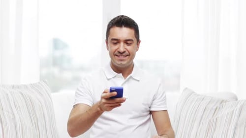 Smiling man talking on smartphone in bright home