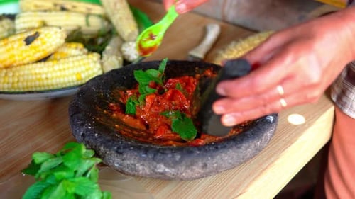 Eine Frau bereitet traditionellen indonesischen Sambal mit einem Steinmörser zu