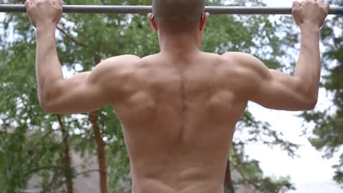 Guy Bodybuilder Pulls Himself Up on the Horizontal Bar