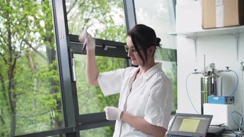 Female in laboratory checking test tube with blood sample, natural background, front middle view