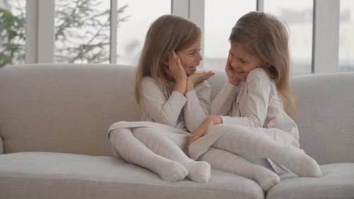 Two Smiling Girls Sitting Together on a Couch