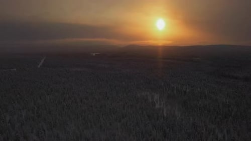Drone flying backwards over snowy wilderness, hazy morning sun in Lapland