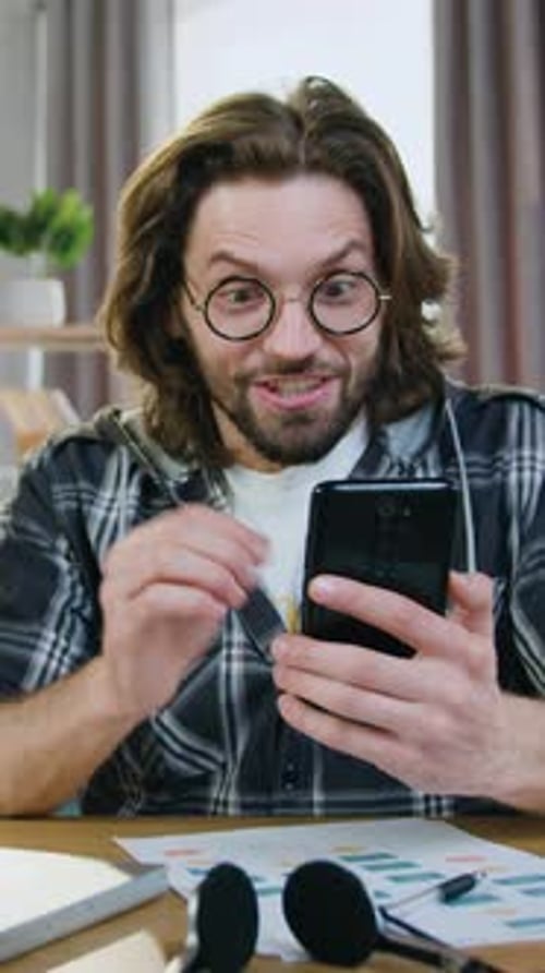 Excited Man Celebrates Good News on Phone Indoors