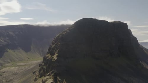 Drone video pulling out from the massive Svalvogar mountain in Iceland and a bright sunny summer day