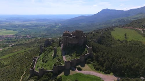 Drone flight toward medieval castle with tilting gimbal, fortress centered in mountainous rural land