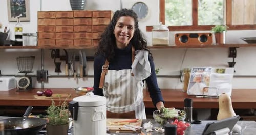 Smiling Woman in Apron Standing in a Well-Equipped Rustic Kitchen