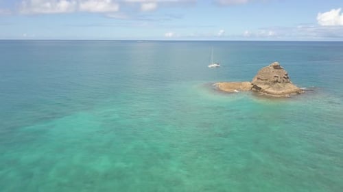 Aerial view of tropical bay and top down flyby of sailboat.