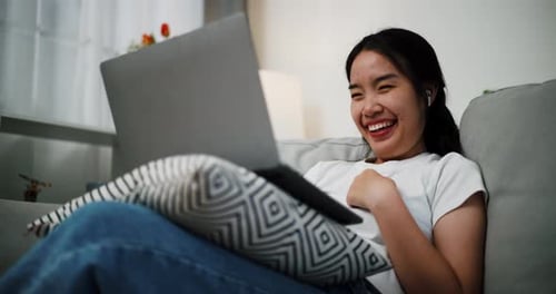 Woman on Sofa Talking on Laptop