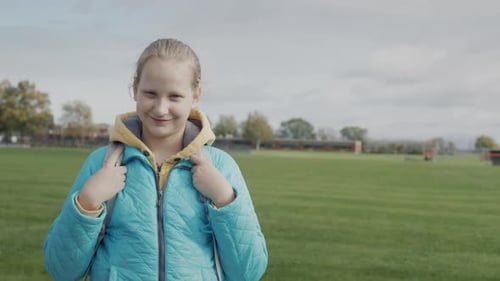 Portrait of a Schoolboy Girl on the Background of a Football Field Near the School