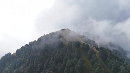 Aerial shot of a high point, or a peak of the mountain covered in clouds in the himachal pradesh.