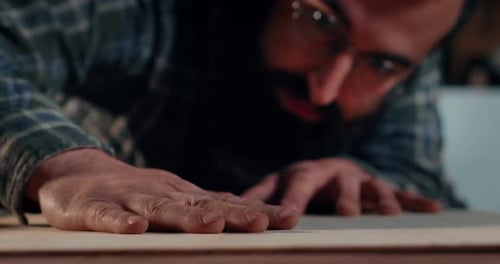 Man Inspecting Smooth Wood in Workshop Close Up