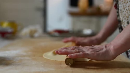 Flattening Dough With a Rolling Pin in Kitchen