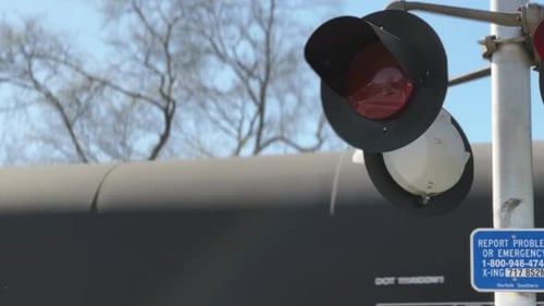 A luz do guarda de travessia ferroviária pisca em vermelho quando o trem passa em segundo plano, 30 fps