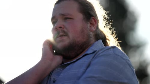 Frustrated young man feeling anxiety and worry standing outdoors in sunlight.