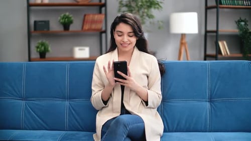 Woman Using Smartphone Relaxing on Couch at Home