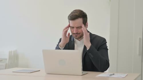 Stressed Young Man Working on Laptop in Office