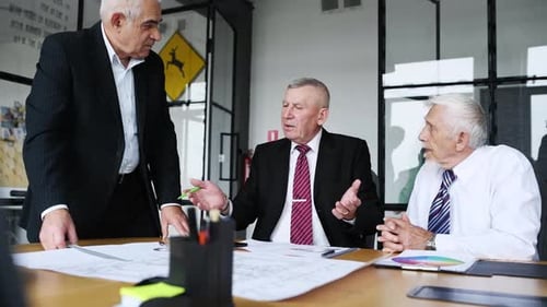 Aged team of elderly businessman architects have a meeting in the office and talking