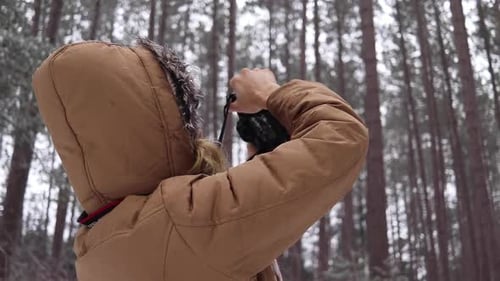 Medium shot of a young women taking photos of a pine forest in Canada.