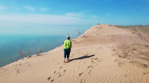 Woman at Desert Dune with Blue Sea at Sunrise