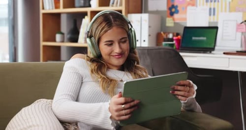 Woman Relaxing on Couch Using Tablet and Headphones