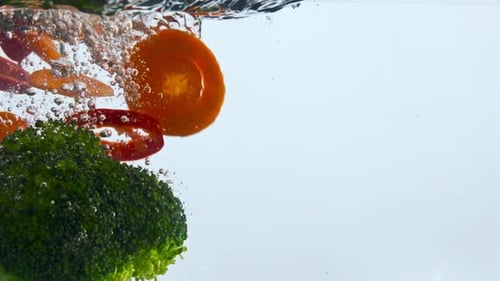 Fresh organic vegetables falling underwater in super slow motion