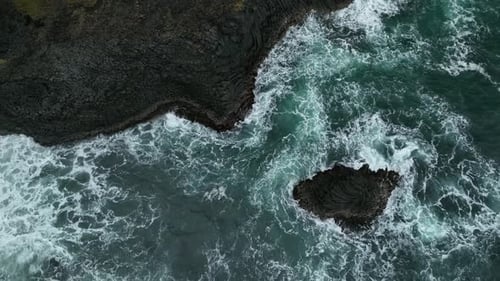 Aerial view of crispy waves breaking on the cliffs along the coast in Iceland.