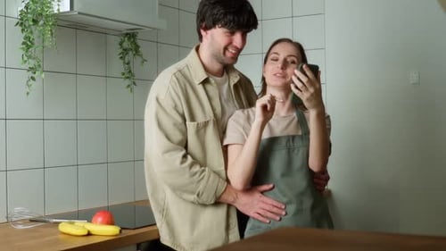 Loving Couple Using Smartphone Together in Kitchen