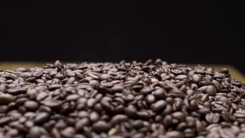 Foto de estudio de primer plano con enfoque superficial, granos de café ricos y oscuros sobre fondo negro