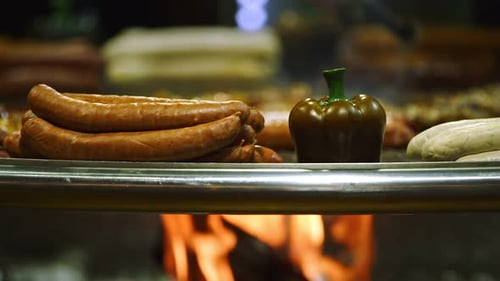 Sausages Cooking on Open Flame Grill at Night