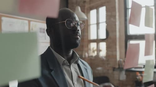 Male Manager Looking at Transparent Wall with Sticky Notes